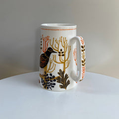 small jug patterned with black bird and trees